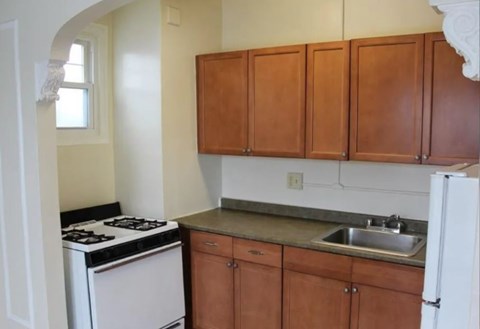 A kitchen with brown cabinets and a white stove.