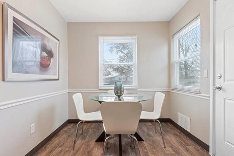 A dining room with a glass table and white chairs.