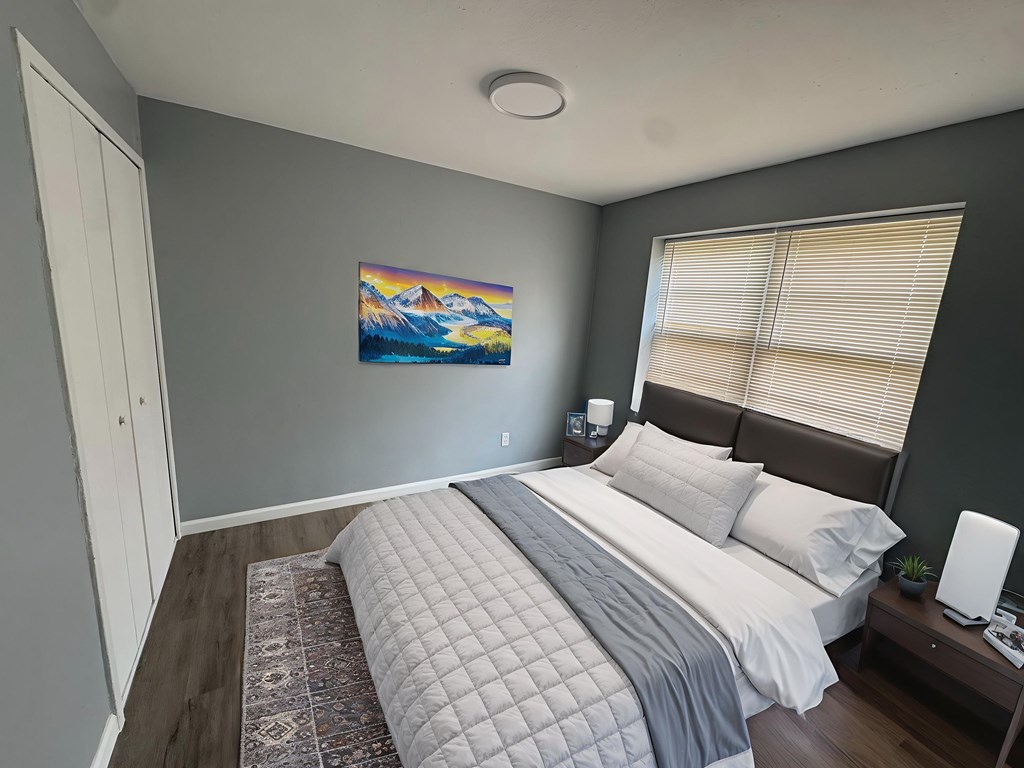 A bedroom with a large bed and a painting on the wall.