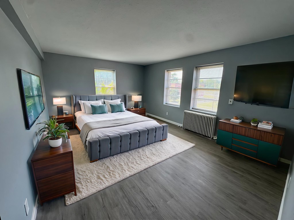 A bedroom with a large bed, a nightstand, and a dresser.