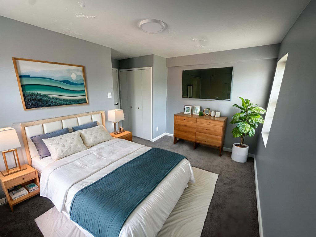 A bedroom with a large bed and a painting on the wall.