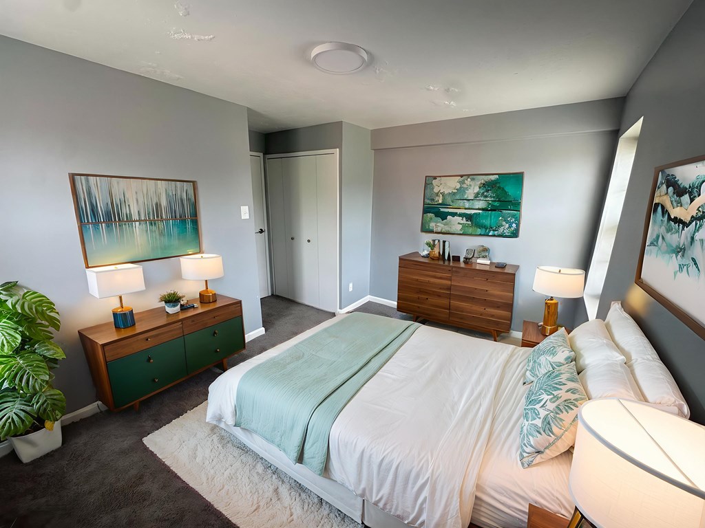 A bedroom with a bed, nightstands, and a painting on the wall.