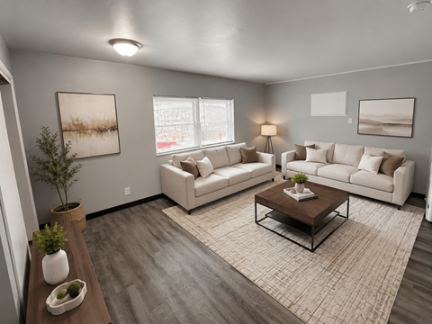 A living room with a white couch, a coffee table, and a plant.
