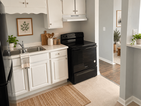 A black fridge and oven in a white kitchen.