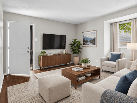 A living room with a white door, a brown coffee table, a white sofa, and a white chair.