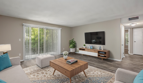 A living room with a wooden coffee table and a flat screen TV mounted on the wall.