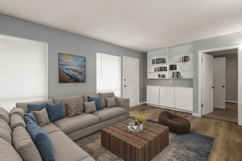 A living room with a grey couch, a brown coffee table, and a painting on the wall.