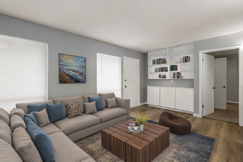 A living room with a grey couch, a brown coffee table, and a painting on the wall.