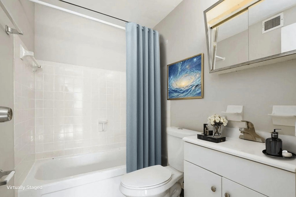A white bathroom with a blue shower curtain and a painting of a galaxy on the wall.