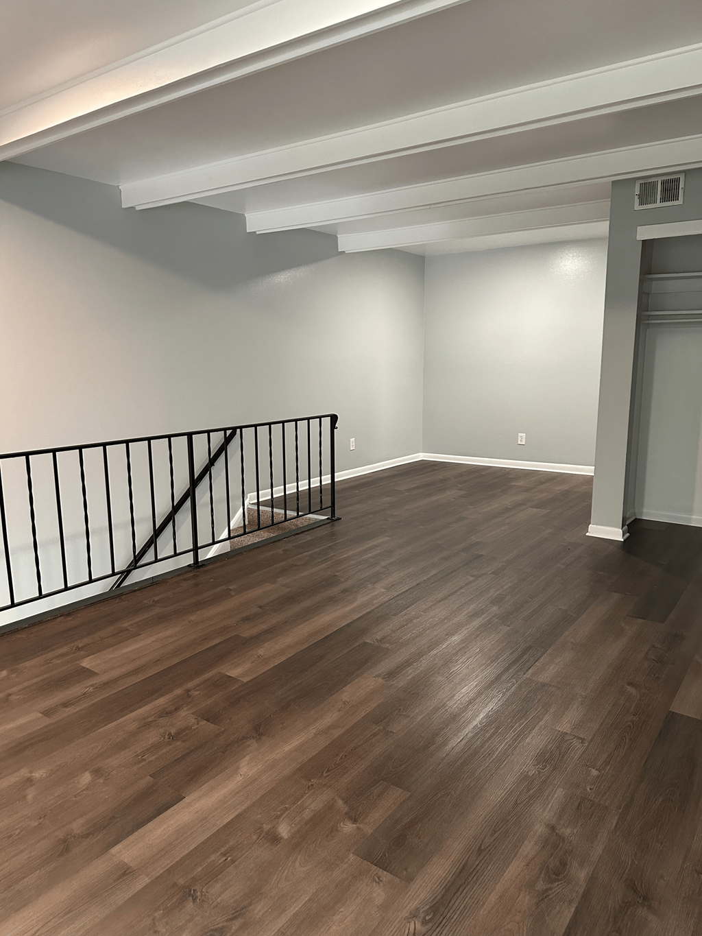 A room with wooden flooring and a black railing.