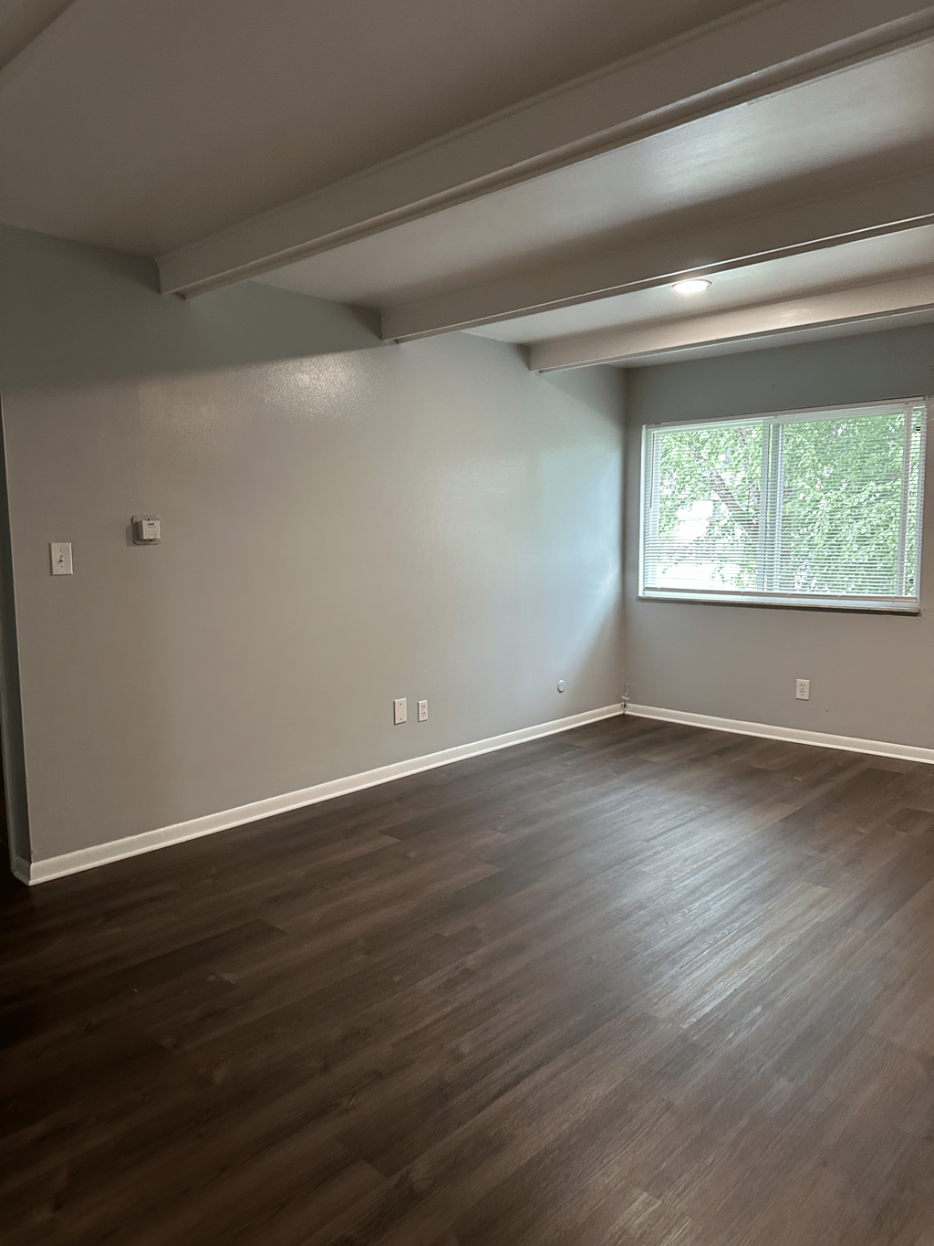 A room with a window and a wooden floor.