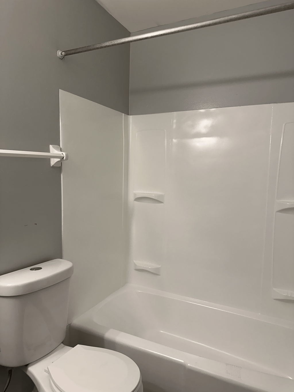 A white toilet sits next to a white bathtub in a small bathroom.