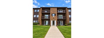 A brown brick apartment building with a white door and windows.