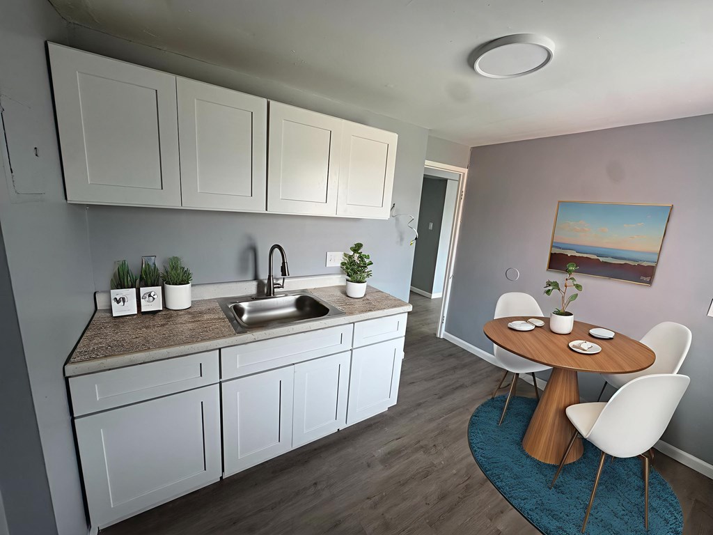 A kitchen with white cabinets and a brown countertop.