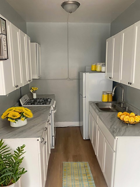 A kitchen with white cabinets and a grey counter top.
