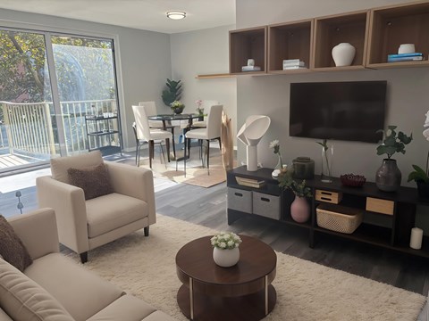 A living room with a white sofa, a wooden coffee table, a flat screen TV, and a dining table with chairs.