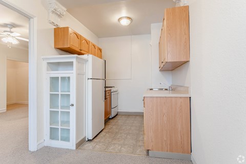 A kitchen with white appliances and wooden cabinets.