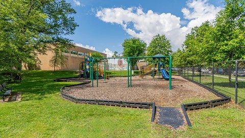A playground with a green swing set and a slide.