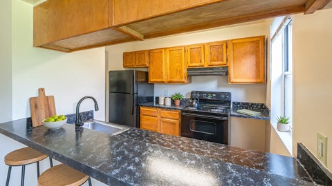 A kitchen with a black granite countertop and wooden cabinets.