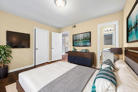 A bedroom with a large bed and a TV on the wall.