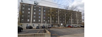 A large grey building with a parking lot in front.