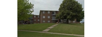 A large brick building with a green lawn in front.