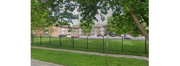 A black metal fence surrounds a green lawn.