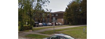 A street view of a residential area with cars parked on the side of the road.