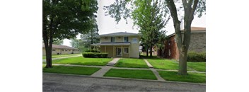 A house with a green lawn and trees in front.