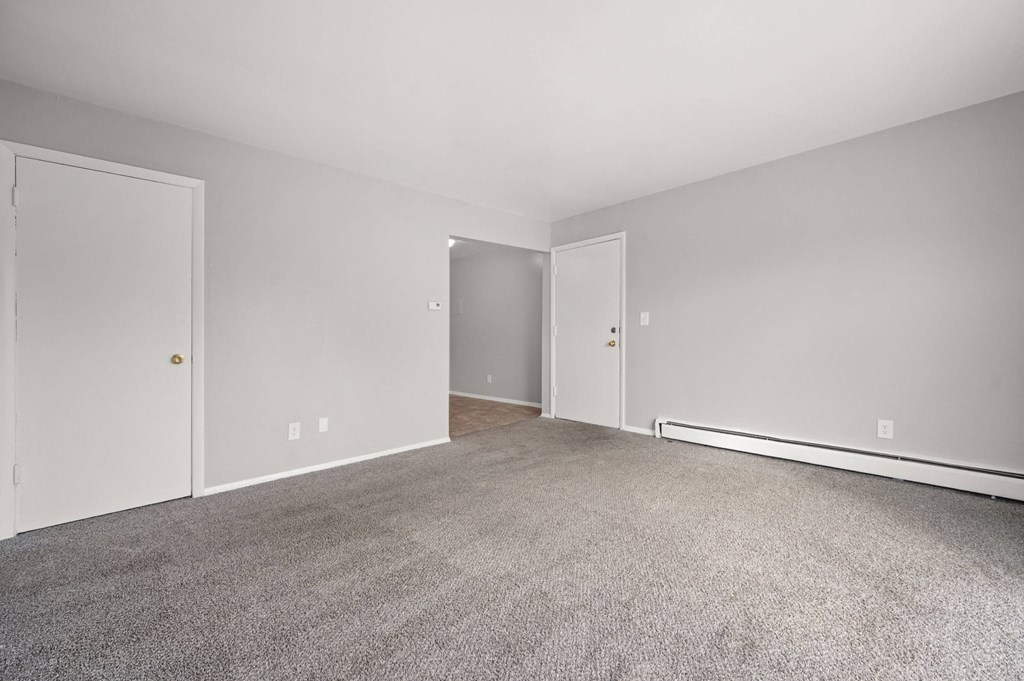 A room with a carpeted floor and two doors.