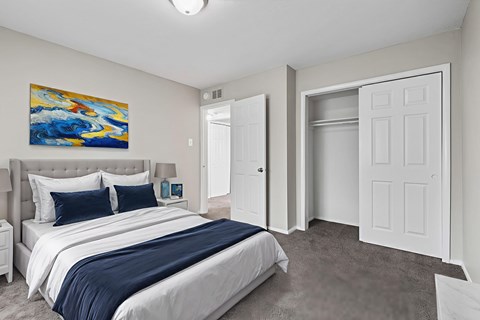 A bedroom with a large bed and a painting on the wall.