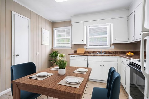 A kitchen with a table set for two with a plant on it.