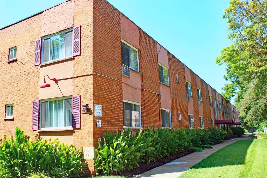 a brick building with purple shutters and a sidewalk in front of it