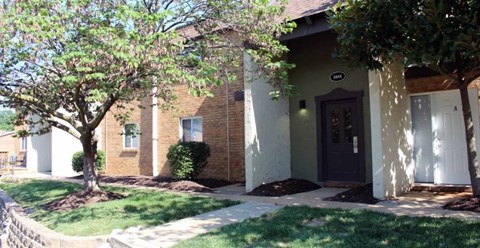 a building with a black door and trees in front of it