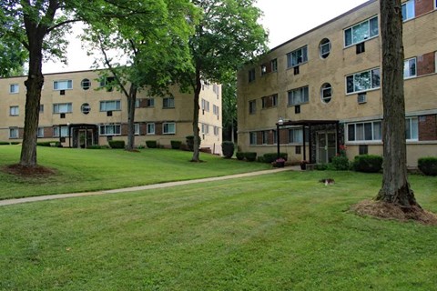 a grassy area with trees in front of a building