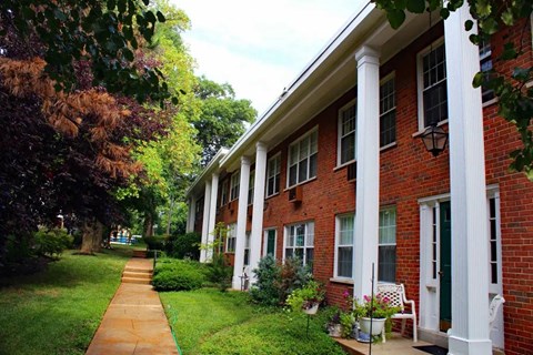 a brick building with white columns and a sidewalk in front of it