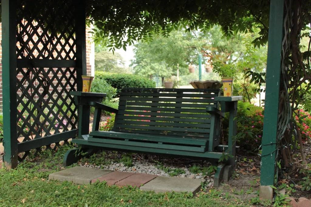 a green bench sitting under a tree in a park