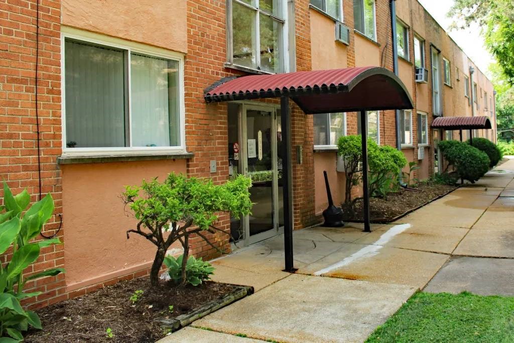 a walkway in front of a brick building with a black awning