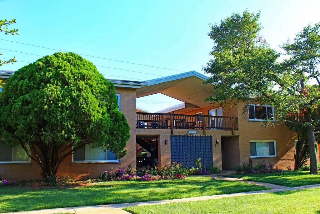 an apartment building with a large tree in front of it