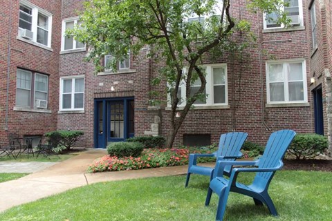 two blue chairs sit in front of an apartment building