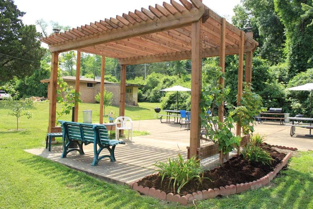 a wooden pergola with a table and benches under it