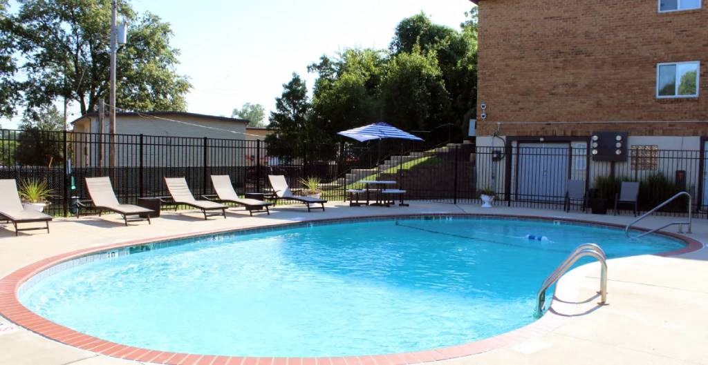 a swimming pool with chaise lounge chairs and a building in the background