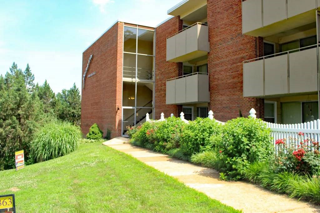 an apartment building with a grassy lawn and a white picket fence in front of it