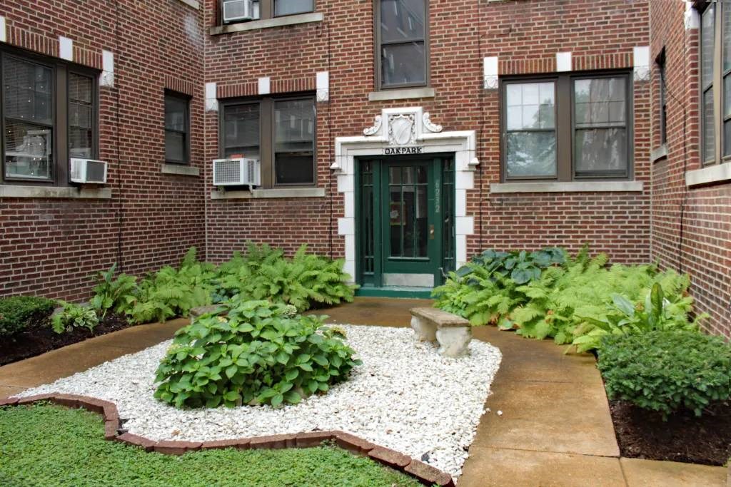 a brick building with a green door and a garden in front of it