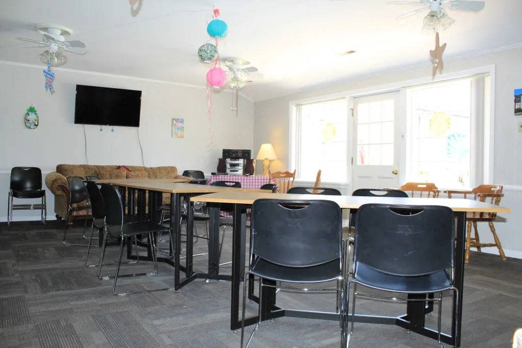 a conference room with tables and chairs and a tv on the wall