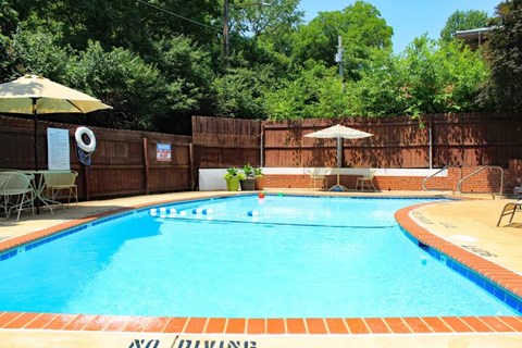 a swimming pool with an umbrella and chairs