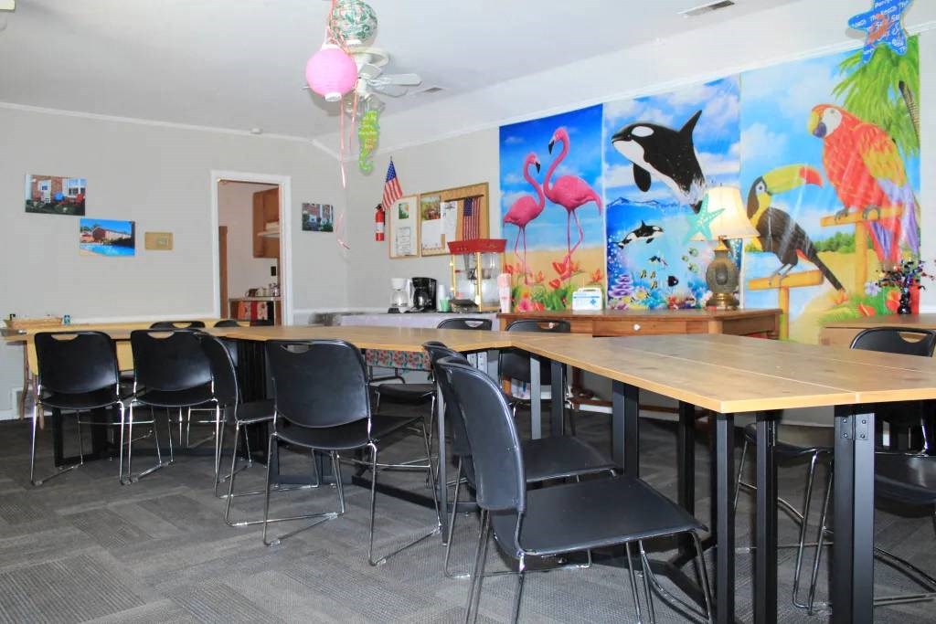 a room with a long table with black chairs and colorful paintings on the wall