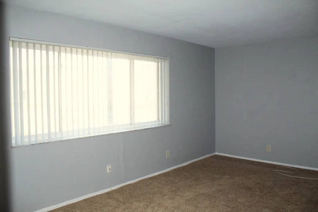 a bedroom with a large window and a carpeted floor