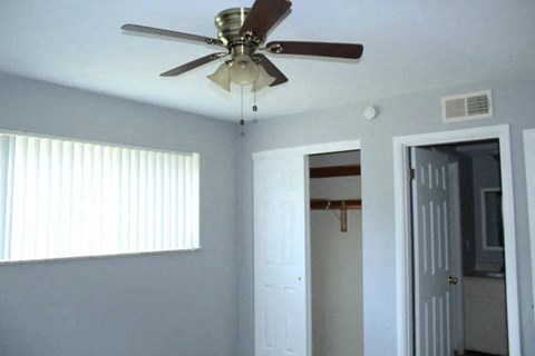 a bedroom with a ceiling fan and a door to a bathroom