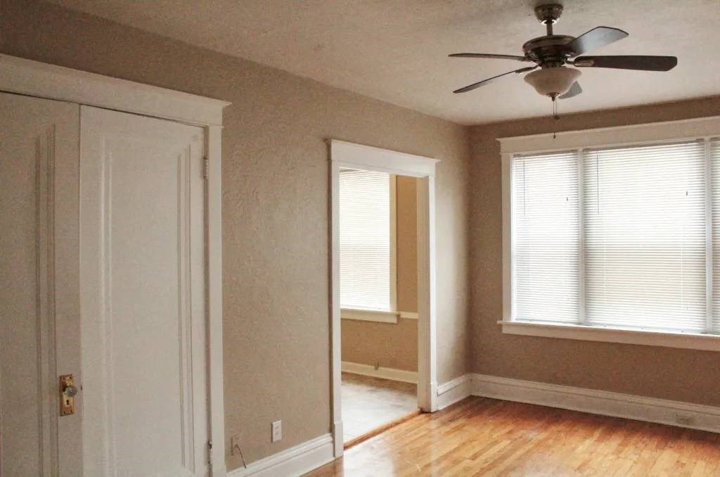 an empty room with a ceiling fan and two windows
